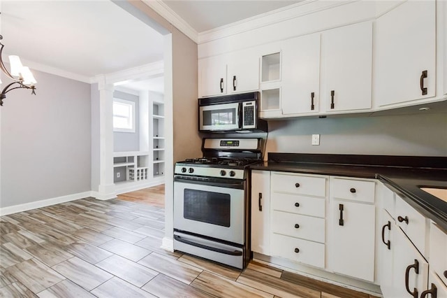 kitchen featuring stainless steel appliances, ornamental molding, dark countertops, white cabinets, and a chandelier