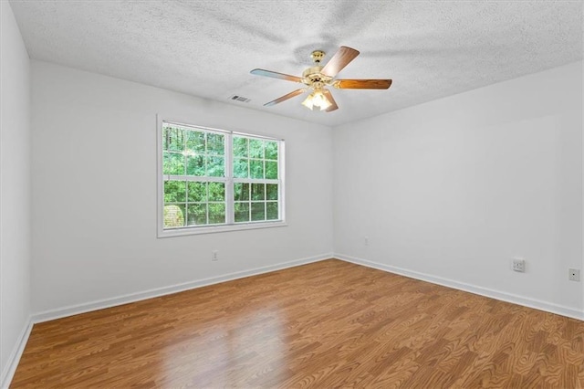 spare room with wood finished floors, a textured ceiling, a ceiling fan, and baseboards