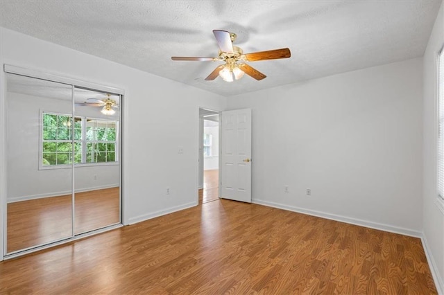 unfurnished bedroom featuring wood finished floors, a closet, baseboards, a textured ceiling, and ceiling fan