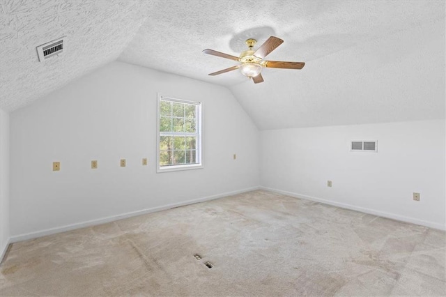 additional living space with a textured ceiling, lofted ceiling, carpet flooring, baseboards, and ceiling fan