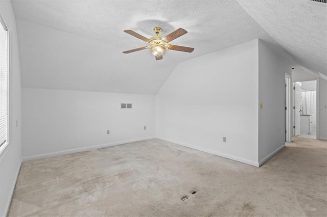 bonus room featuring vaulted ceiling, carpet flooring, ceiling fan, baseboards, and a textured ceiling