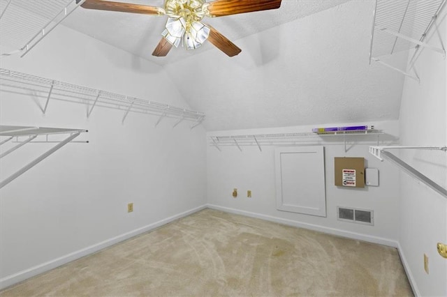 walk in closet with lofted ceiling, light colored carpet, and a ceiling fan