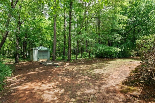 view of yard with a storage unit, an outbuilding, and a view of trees