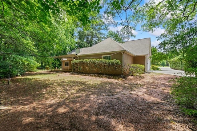 view of side of property featuring driveway, a garage, and stucco siding