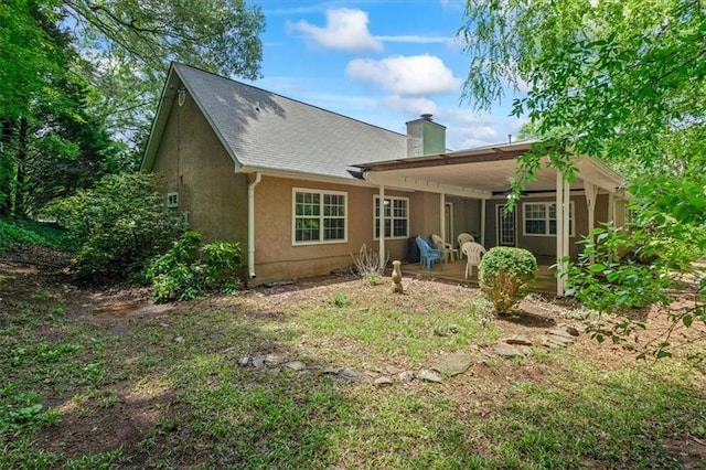back of property featuring a chimney, a patio area, and stucco siding