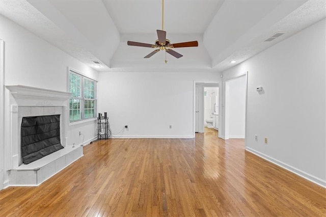 unfurnished living room featuring a ceiling fan, wood finished floors, a fireplace, baseboards, and vaulted ceiling
