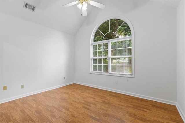 empty room with lofted ceiling, a ceiling fan, wood finished floors, and baseboards