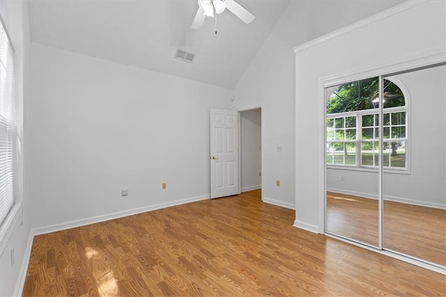 unfurnished bedroom featuring high vaulted ceiling, light wood-style flooring, a ceiling fan, baseboards, and a closet