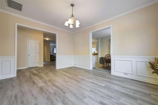 unfurnished room with crown molding, light hardwood / wood-style flooring, and a notable chandelier