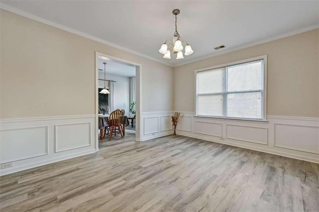 spare room featuring light hardwood / wood-style floors, crown molding, and a chandelier