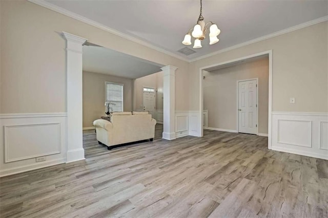 unfurnished dining area featuring light hardwood / wood-style flooring, an inviting chandelier, decorative columns, and crown molding