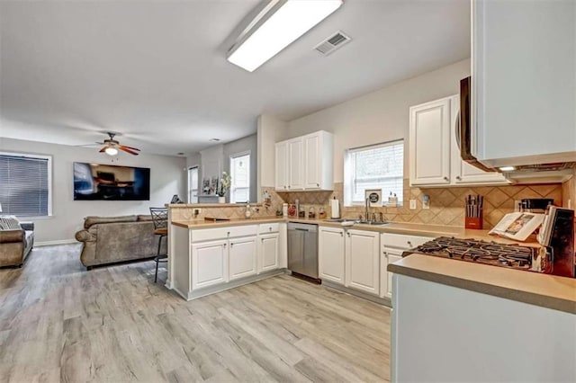 kitchen with white cabinets, light hardwood / wood-style flooring, stainless steel dishwasher, tasteful backsplash, and kitchen peninsula