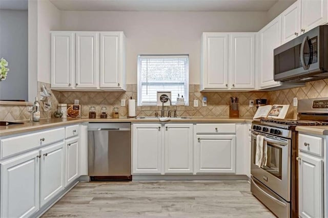 kitchen featuring white cabinets, sink, appliances with stainless steel finishes, and light hardwood / wood-style flooring