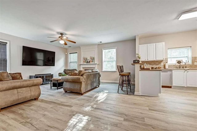 living room featuring ceiling fan, sink, and light hardwood / wood-style flooring