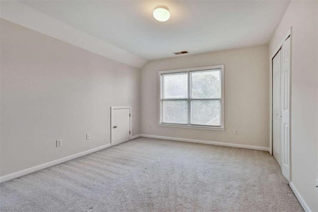 unfurnished bedroom featuring light carpet and vaulted ceiling