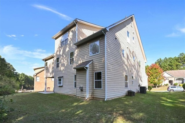 rear view of house featuring central AC unit and a lawn