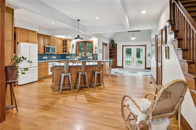 kitchen featuring a kitchen breakfast bar, light hardwood / wood-style flooring, french doors, white appliances, and beam ceiling