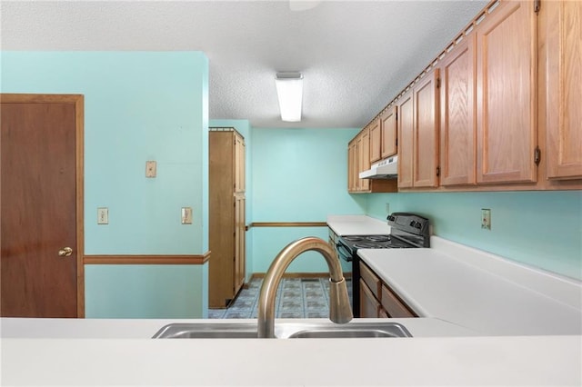 kitchen featuring light countertops, a textured ceiling, under cabinet range hood, a sink, and black / electric stove