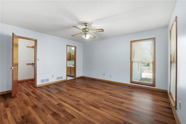 empty room with a ceiling fan, baseboards, visible vents, and wood finished floors