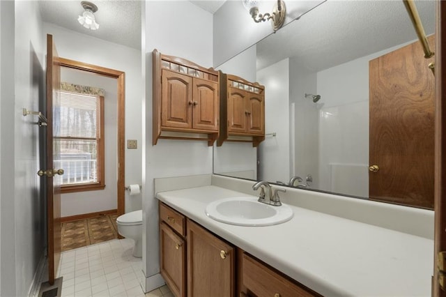 bathroom with tile patterned flooring, vanity, toilet, walk in shower, and a textured ceiling