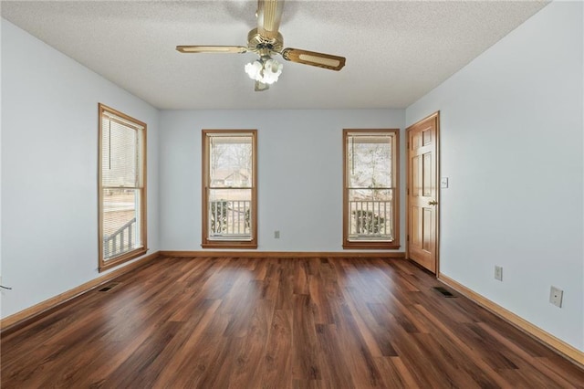 spare room with a textured ceiling, dark wood finished floors, and a wealth of natural light