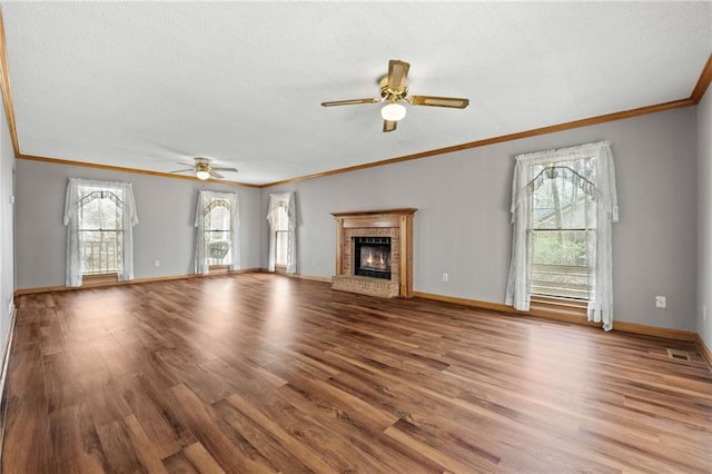 unfurnished living room with crown molding, a brick fireplace, a textured ceiling, a ceiling fan, and wood finished floors