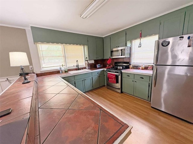 1146 Nelson St, Jackson, GA 30233 - kitchen with stainless steel appliances, green cabinetry, tile counters, light wood finished floors, and ornamental molding