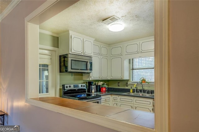 kitchen featuring appliances with stainless steel finishes, white cabinetry, sink, crown molding, and a textured ceiling