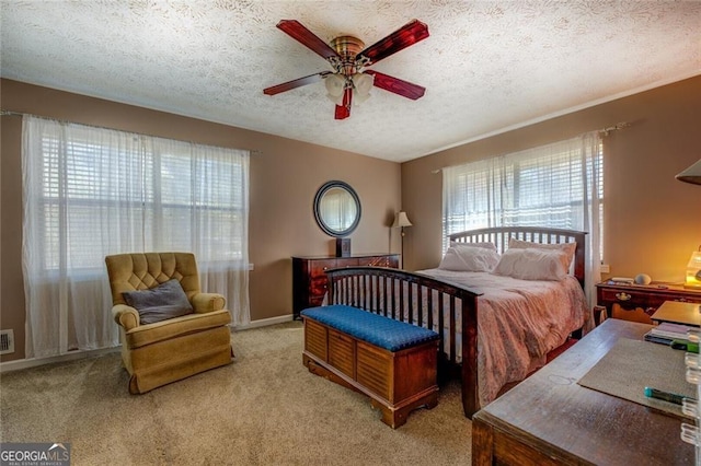 bedroom with ceiling fan, light colored carpet, and a textured ceiling