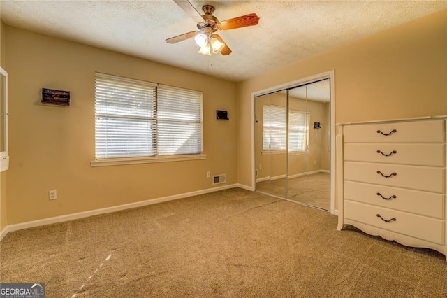 unfurnished bedroom featuring ceiling fan, light colored carpet, a closet, and a textured ceiling