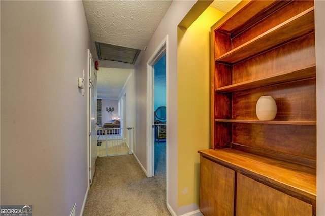 hall featuring light colored carpet and a textured ceiling