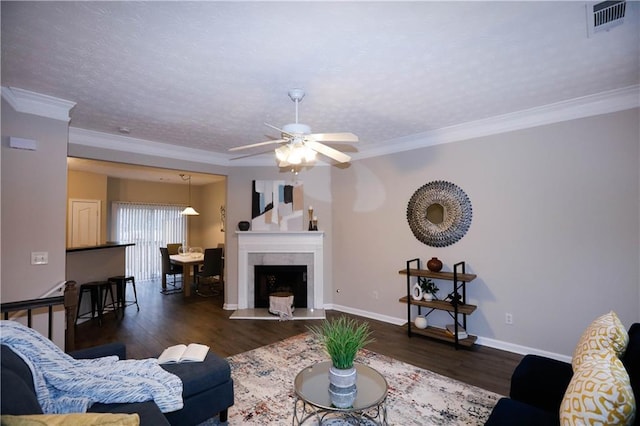 living room featuring ceiling fan, ornamental molding, dark hardwood / wood-style floors, and a textured ceiling