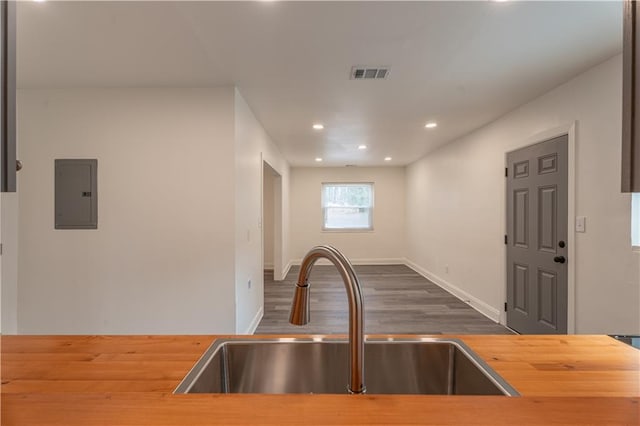 kitchen with hardwood / wood-style flooring, wooden counters, sink, and electric panel