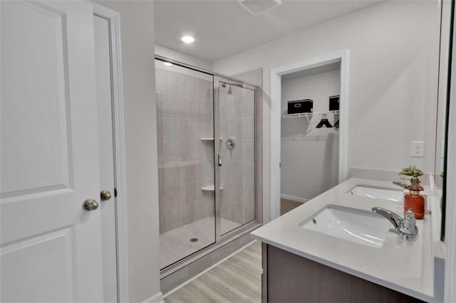 2766 Aralynn Way, College Park, GA 30337 - bathroom with a stall shower, double vanity, a walk in closet, wood finished floors, and recessed lighting