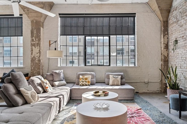 living area with brick wall, concrete floors, a ceiling fan, and a towering ceiling