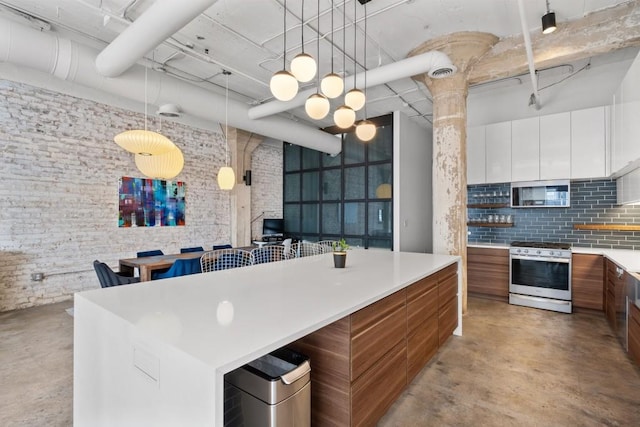 kitchen featuring stainless steel microwave, concrete flooring, modern cabinets, and gas range oven