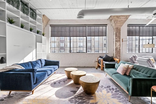 living room with plenty of natural light, brick wall, and concrete floors