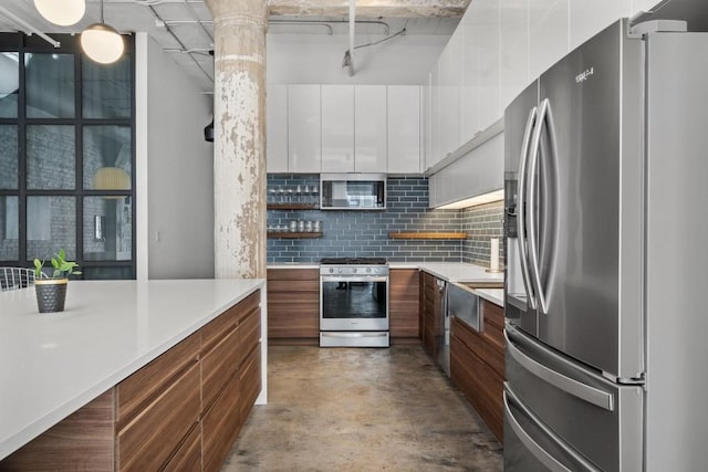 kitchen featuring decorative backsplash, white cabinetry, appliances with stainless steel finishes, and modern cabinets