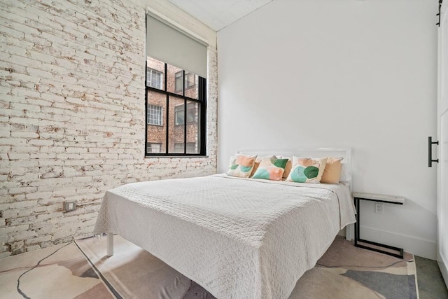 bedroom with baseboards and brick wall