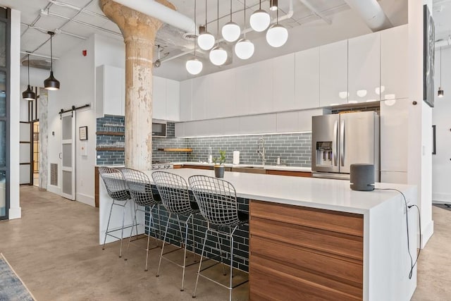 kitchen featuring stainless steel fridge with ice dispenser, white cabinets, a kitchen breakfast bar, and decorative light fixtures