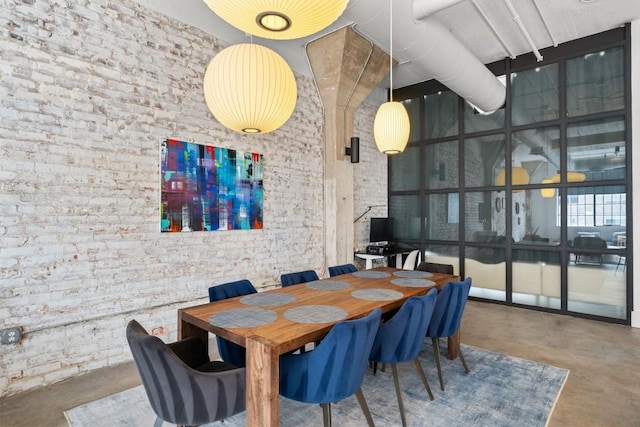 dining room featuring brick wall, concrete floors, and a towering ceiling