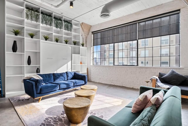 living area with visible vents, brick wall, and concrete flooring