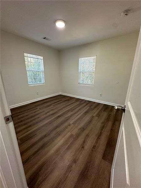 unfurnished room featuring dark wood-style flooring and baseboards