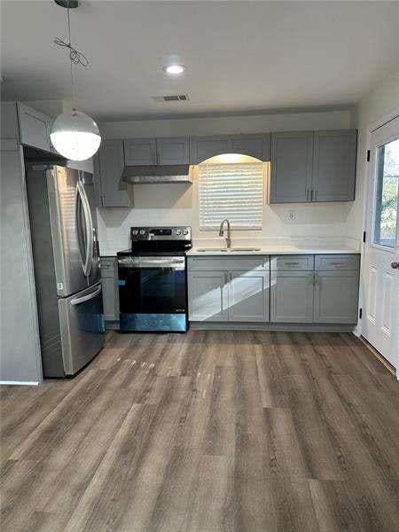 kitchen with a sink, dark wood-style flooring, gray cabinetry, and stainless steel appliances