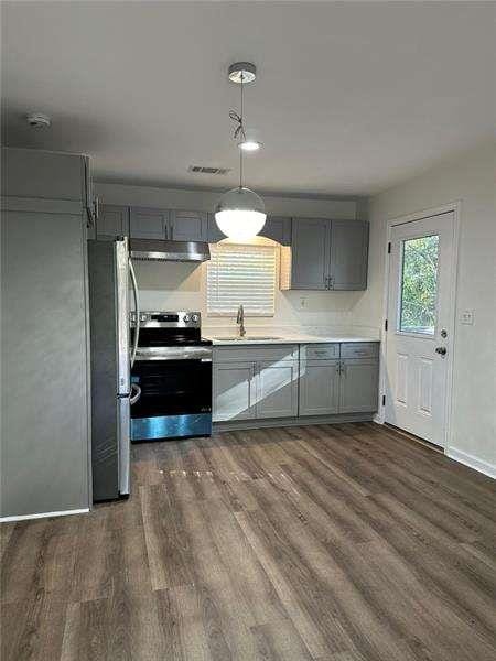 kitchen with a sink, appliances with stainless steel finishes, gray cabinets, and dark wood-type flooring