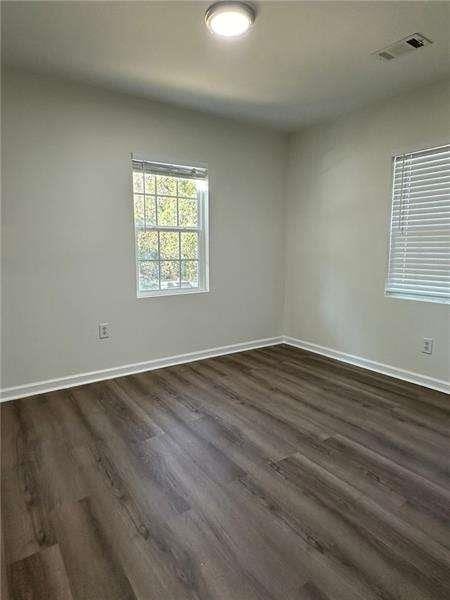 unfurnished room with visible vents, baseboards, and dark wood-style floors
