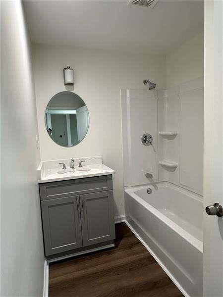 bathroom featuring vanity, shower / bathtub combination, wood finished floors, and visible vents