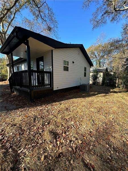 view of side of property featuring a porch and central AC