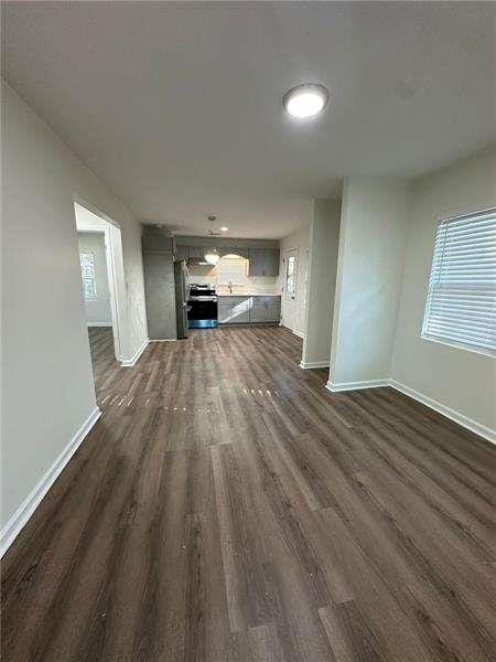 unfurnished living room featuring baseboards and dark wood-type flooring