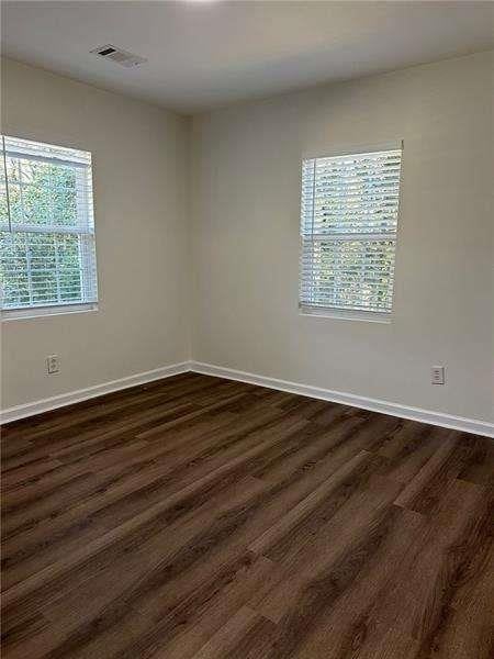 spare room featuring baseboards, dark wood-style flooring, and visible vents